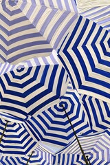 Obraz premium Vibrant Blue and White Striped Beach Umbrellas Create a Cheerful Overhead Canopy on a Sunny Day