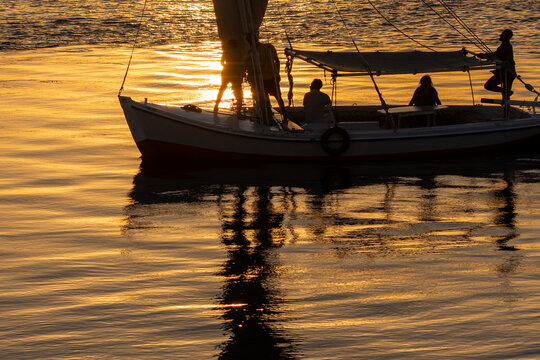 Felucca and passenger silhouettes on the Nile at sunset in Luxor