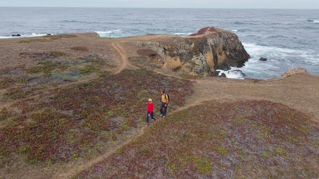 Mature couple hikes along cliffs in Mendocino or Fort Bragg with stunning ocean views and waves crashing below them.