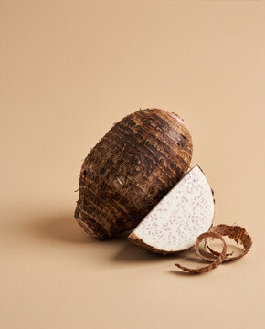 s (Taro)
Title: Fresh Taro Root Sliced Showing White Speckled Flesh, Raw Talas Tuber on Beige Studio Background