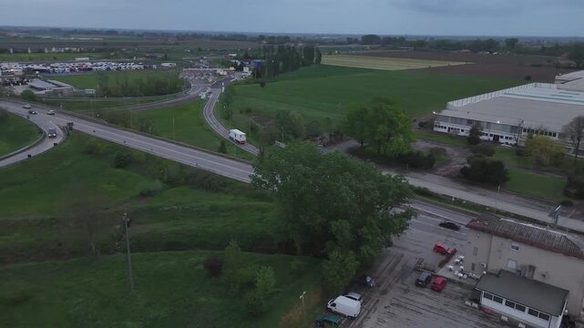 Aerial view of highway intersection and industrial area with moving vehicles in cloudy weather.