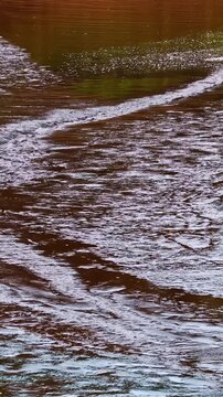 Turbulent river water flow with strong current patterns moving downstream.