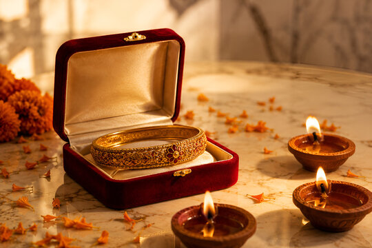 Traditional Gold Bangle in Red Velvet Box with Clay Diyas and Marigold Petals
