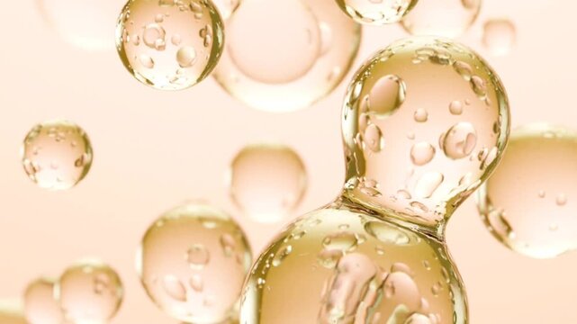 Abstract golden oil bubbles floating in liquid essence for skincare cosmetic background providing cinematic slow motion footage of glowing luxury serum drops.