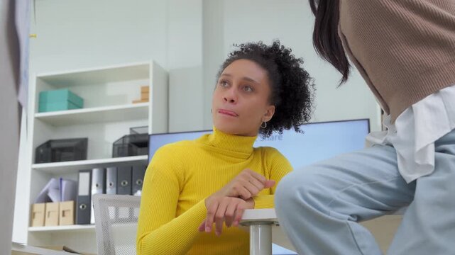 Diverse colleagues laughing together during coffee break at office desk, casual friendly conversation between coworkers, multicultural workplace friendship and connection concept