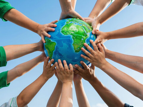 Multiple hands holding a globe together against a blue sky background