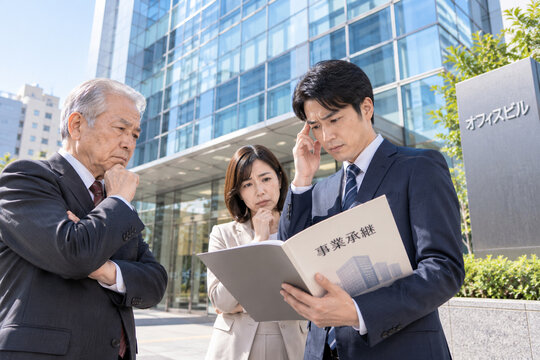 オフィスビル前で事業承継に悩む経営者・後継者