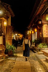 Obraz premium Woman walking away down lantern-lit alley at night, Shaxi Ancient Town, Yunnan, China