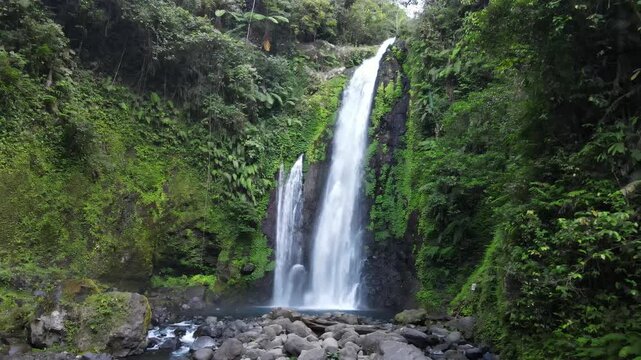Aerial Footage of Gomblang Waterfall Flowing Through a Tropical Forest with Pristine Water, Wild Trees, and Large Rocks During Morning in Indonesia. The Scenic Cascade and Dense Wilderness from Above.