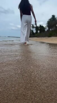 Woman walking along a sandy beach in Batticaloa, Sri Lanka