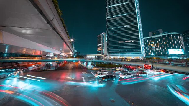 Night time lapse of busy urban traffic flow in modern city center with light trails.