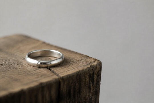 Silver band ring on rough wooden block, minimal still life