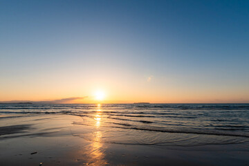Fototapeta premium Sunset over the ocean with golden reflections on a beach in Fukuoka, Japan