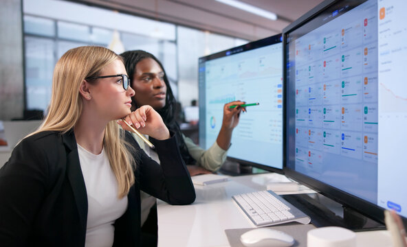 Two Women Managers Discussing Data Analysis While Working