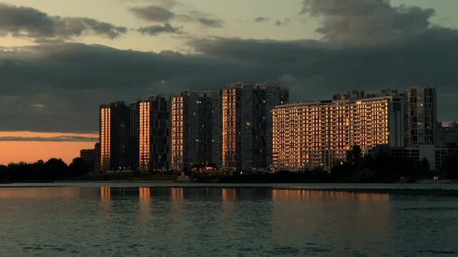 Residential High-Rise Buildings at Blue Hour Reflecting on Water: Modern Apartment Complex Skyline with Golden Windows | Urban Waterfront Evening | City Lights Reflection