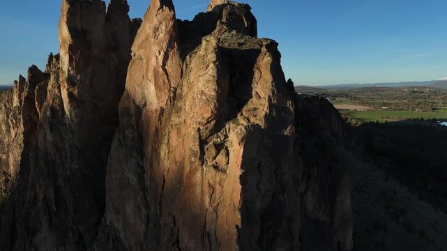 Smith Rock State Park towering volcanic tuff spires and cliffs illuminated by golden hour light in Oregon 4k aerial drone video