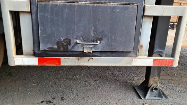 Commercial semi-truck undercarriage featuring a heavy-duty steel utility toolbox and safety reflective tape for freight transport maintenance.