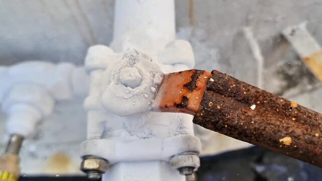 Heavy frost and ice buildup on an industrial HVAC refrigeration pipe valve, indicating extreme subzero cooling or system freezing.