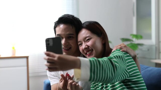 Asian couple are having fun taking selfies with their smartphones, having a relaxing time together.