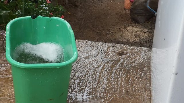 Rainwater Pouring into Green Plastic Bucket Creating White Foam