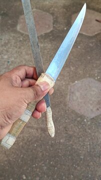 Hand Holding Kitchen Knife and Metal File Tool for Sharpening