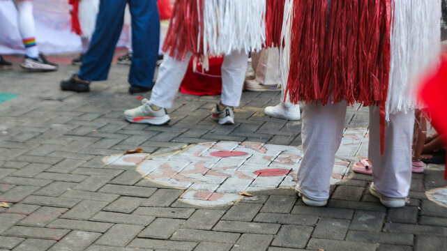 People in Traditional Red and White Costumes Walking on Street with Tiger Chalk Art during Festival