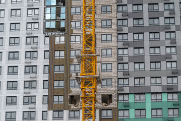 Construction progress on a new urban building showcasing a large yellow crane against modern architecture © beholdereye