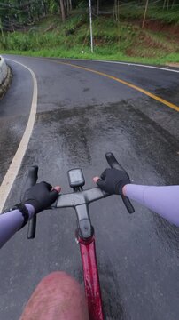 View from a cyclist's perspective on a wet road surrounded by lush greenery, capturing the essence of outdoor adventure.