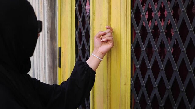 Woman knocks on a yellow city door