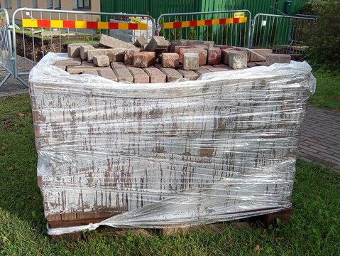 Pallet of Paving Bricks Wrapped in Plastic on Construction Site.

