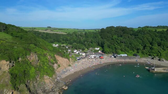 Polkerris, South Cornwall, England: DRONE VIEWS: 1. Polkerris beach and village; 2. Village houses, harbour wall, sunbathers on the beach and swimmers. Polkerris is located close to Par Sands.