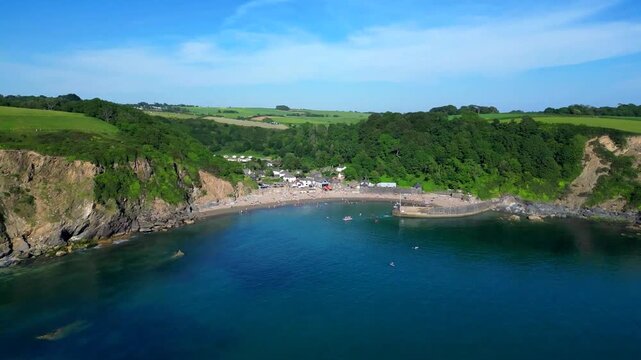 Polkerris, South Cornwall, England: DRONE VIEWS: 1. Polkerris beach and village; 2. Village houses, harbour wall, sunbathers on the beach and swimmers. Polkerris is located close to Par Sands.