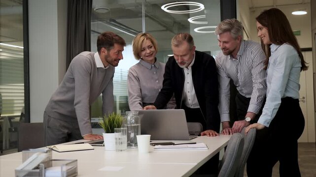 Business people discussing work together using a tablet and laptop taking notes in a modern office