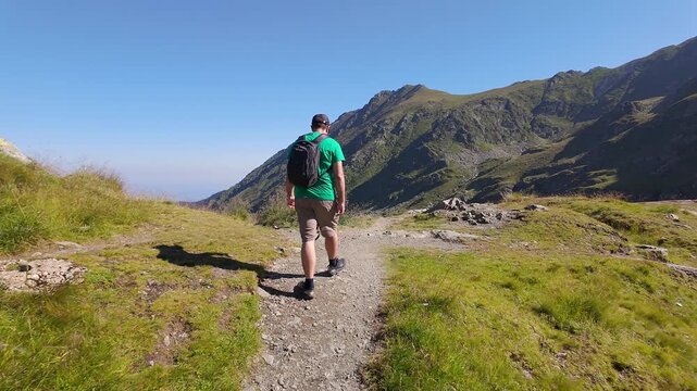 Solo traveler hiking through the Carpathian Mountains in Romania on a sunny summer adventure
