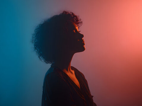 Soft profile portrait of person with glowing aura silhouette in moody blue and orange lighting, contemplative expression and dramatic contrast
