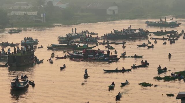 Traders and locals exchange goods on small wooden boats at the Lok Baintan Floating Market at dawn