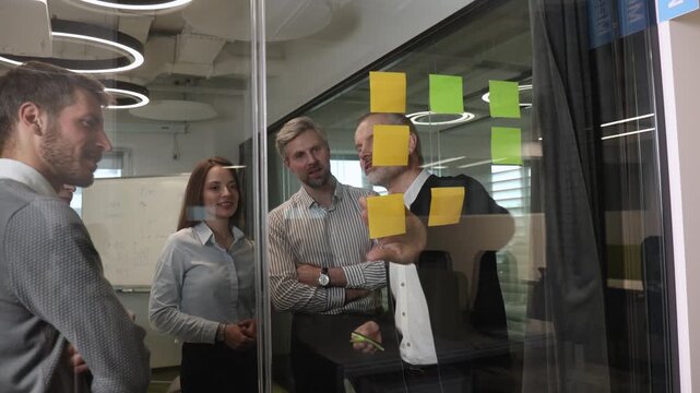 Creative group or business people planning innovation with sticky notes on glass wall.