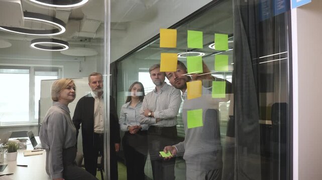 Creative group or business people planning innovation with sticky notes on glass wall.