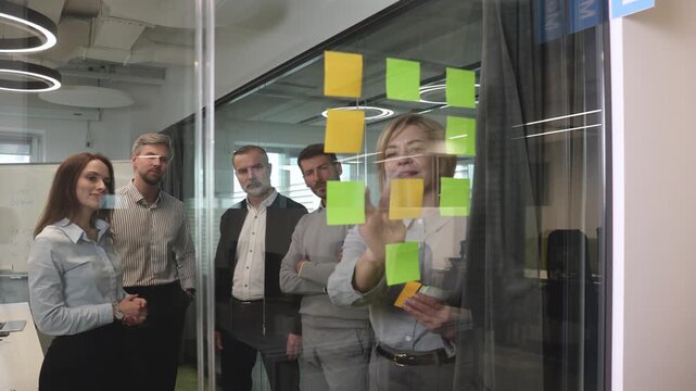 Creative group or business people planning innovation with sticky notes on glass wall.