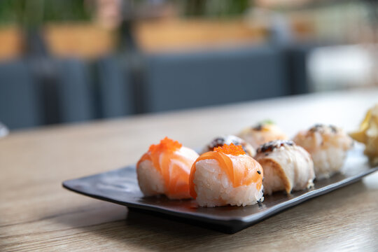 Temarizushi or Japanese rice balls served on the black plate in the restaurant Temari zushi with shrimp, crab, salmon, eel. Japanese Temarizushi. Selective focus.