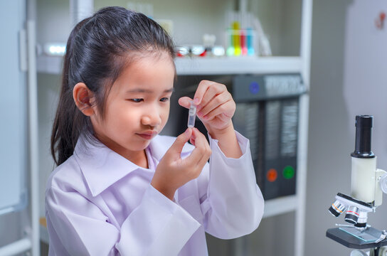 Asian girl scientist examining test tube sample in laboratory for stem education and school learning concept	