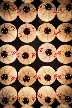 Hynoptic pattern of illuminated traditional Japanese paper lanterns with eye designs aligned in darkness