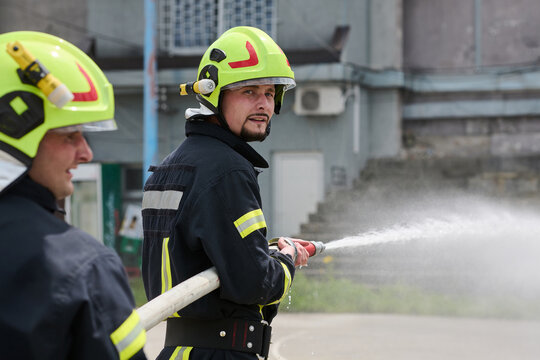 Firefighter Team Using Hose To Spray Water During Training Or Emergency Response