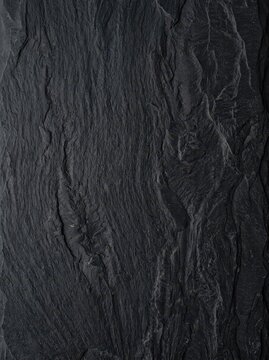 Natural Dark Black Slate Stone Texture Background with Rough Vertical Ridges and Organic Surface Details