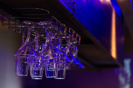 Hanging Martini Glasses and Tumblers Under Blue Neon Bar Lights
