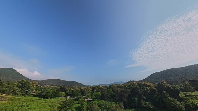 Scenic mountain landscape with lush green forest, rolling hills and blue sky with clouds, creating a peaceful tropical nature and travel background.