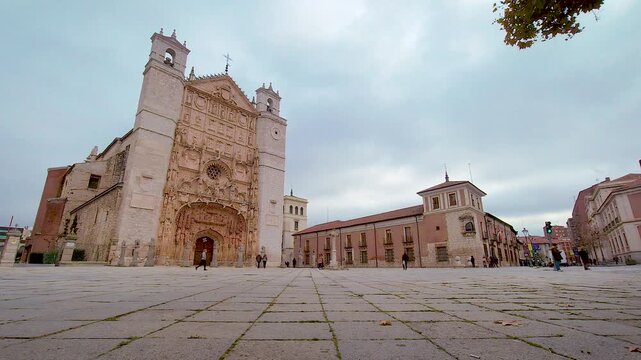 People walking across San Pablo square in front of historic church in Valladolid Spain.