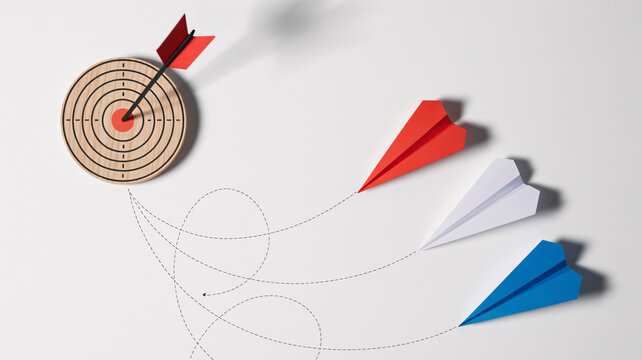 Minimalist business target concept, paper airplanes flying toward wooden bullseye, successful marketing strategy and goal achievement