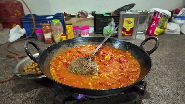 Tomato Gravy Simmering in Large Iron Wok for Indian Curry Preparation