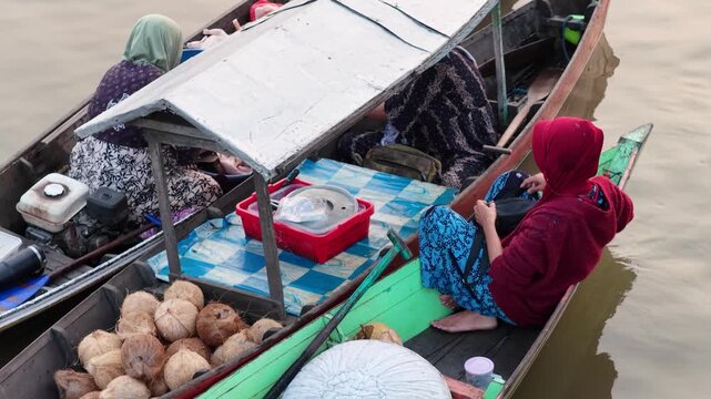Local merchants trade fresh coconuts from wooden boats at Lok Baintan Floating Market in Kalimantan